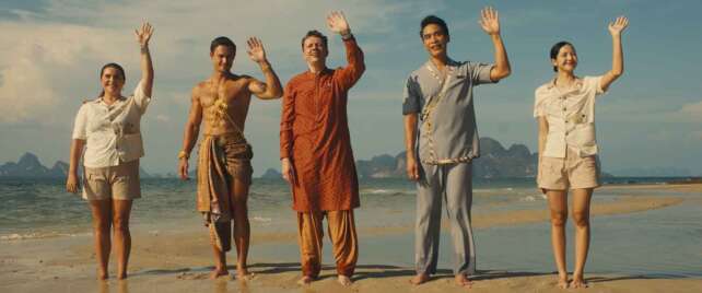 The White Lotus on HBO Canada. Pictured (left to right): Morgana O'reilly, Arnas Fedaravicius, Christian Friedel, Dom Hetrakul, Lalisa Manobal, waving while standing in the sand at the beach.