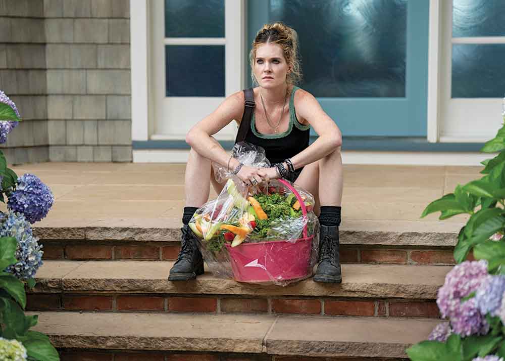 Sirens on Netflix. Pictured: Receiving an edible arrangement of fruit from her sister sends Devon (Meghann Fahy) on a mission.