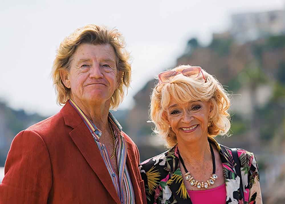 The Madame Blanc Mysteries on Acorn TV. Pictured: Jean’s friends Jeremy and Judith Lloyd Hames (Robin Askwith and Sue Holderness).