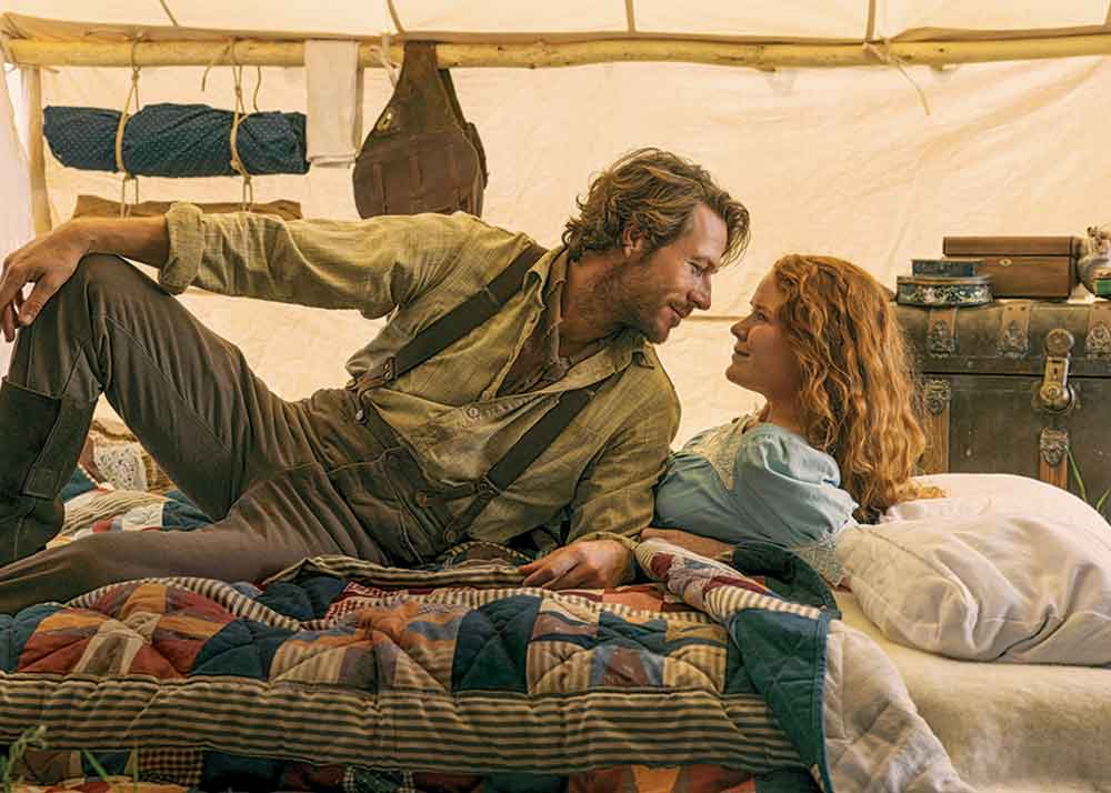 Little House on the Prairie on Netflix. Pictured: Charles and Caroline Ingalls, played by Luke Bracey and Crosby Fitzgerald.